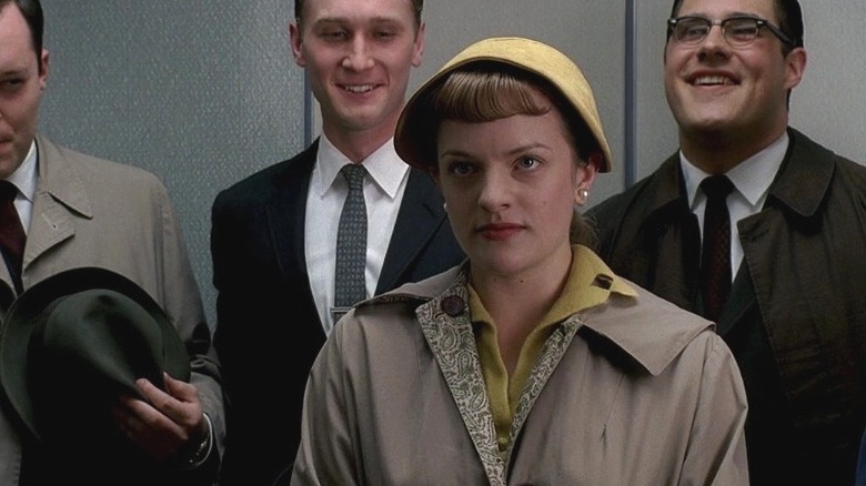 Peggy standing in elevator with workers