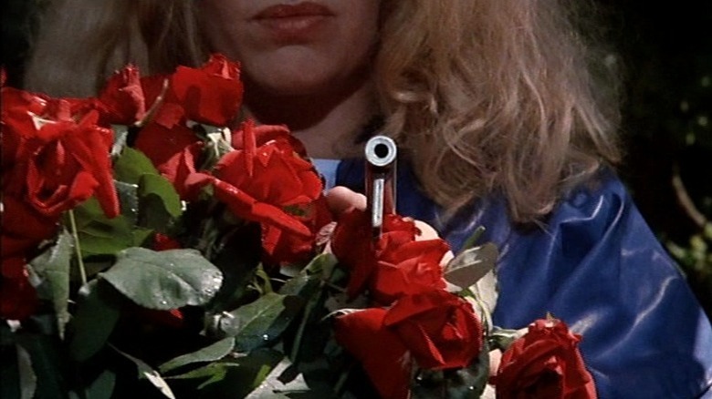 Woman holding gun over red rose bouquet in The 4th Man