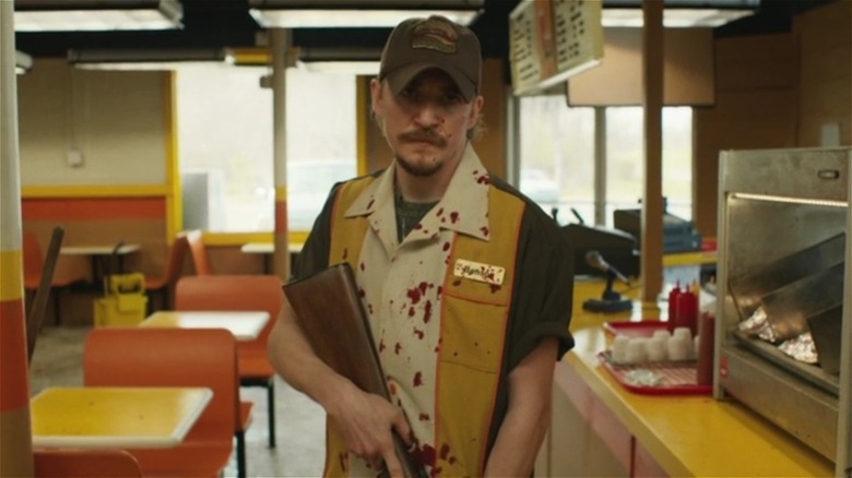 A bloody Kyle Gallner holding a rifle in The Passenger